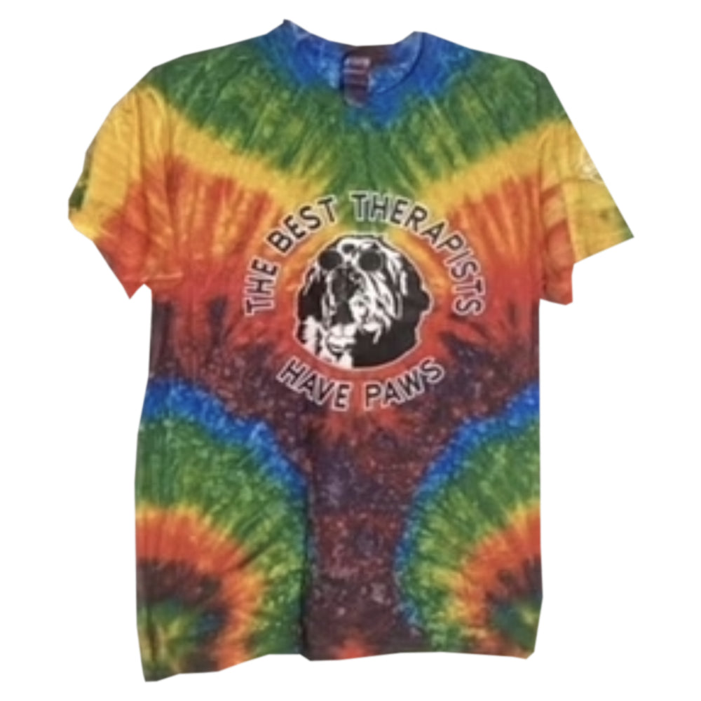 Colorful tie-dye t-shirt featuring the phrase "The Best Therapists Have Paws" with a black and white paw print and dog silhouette in a circular design.
